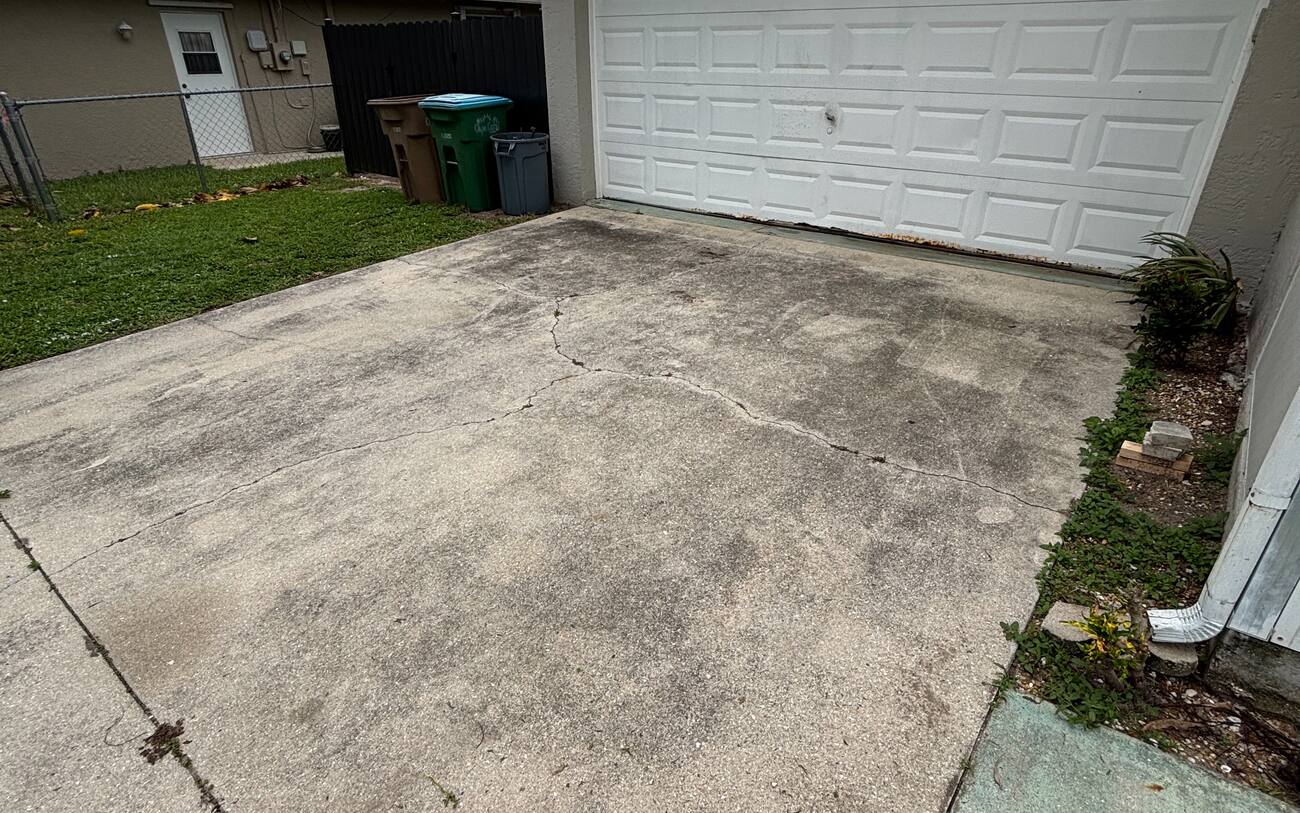 Driveway cleaning before in Cape Coral FL — dirty stained concrete by J Property Services